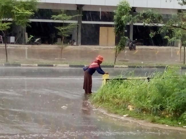 Tak Hiraukan Hujan Deras, Perempuan Ini Menyapu Jalan di Kota Batam