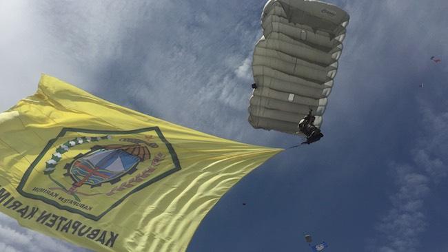 Aksi Prajurit Marinir Terjun Payung Sembari Bawa Bendera